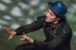 Puck wearing his blue sequined bowler and green sequined vest squats with his hands expressively held out before him, and you can see the dappled light on the stage.