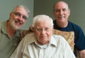 Portrait of my dad sitting in a chair with me on one side and my brother, John, on the other.